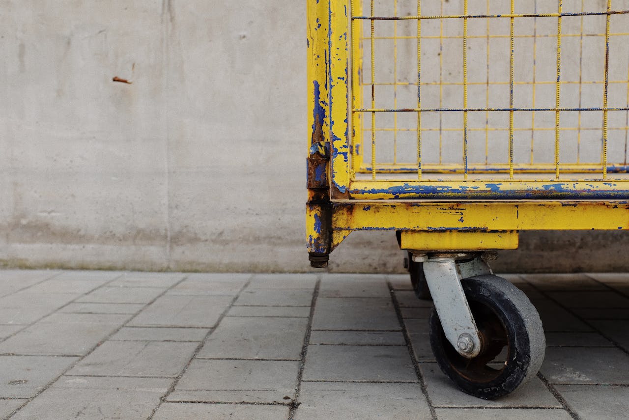 Mastering the First Impression: Your intriguing post title goes here Detailed view of a rusty yellow industrial cart wheel on a paved surface.